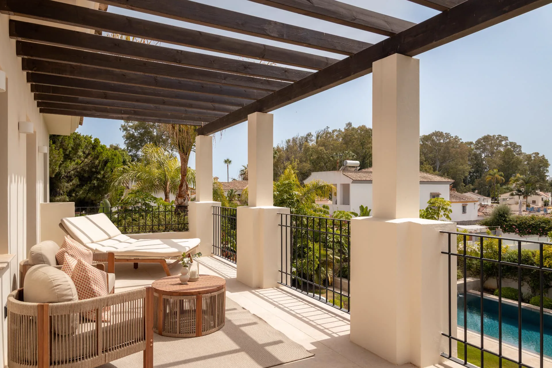 A private upper terrace beneath dark timber beams, overlooking the pool