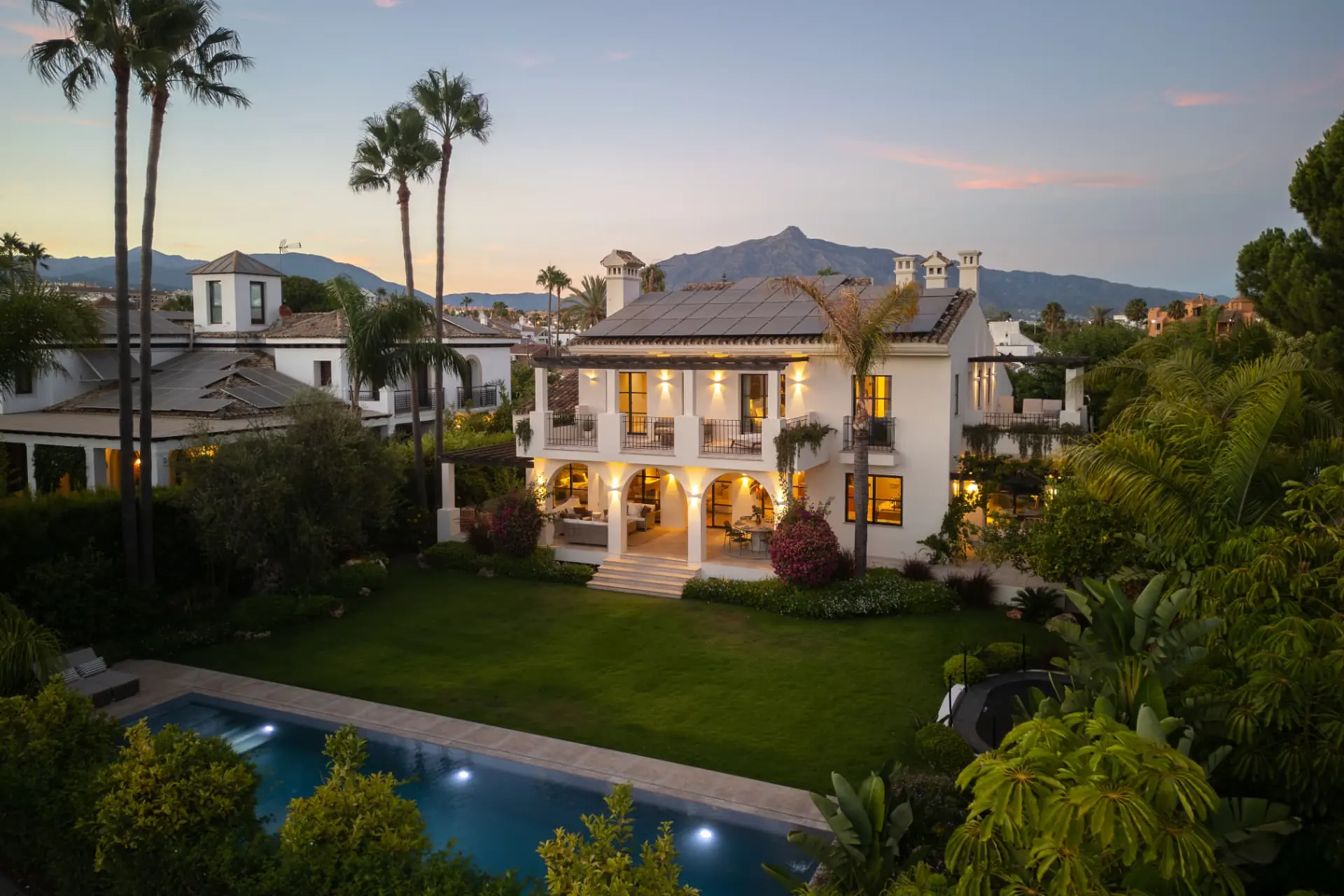 La Serena at dusk: the lit loggia and terraces above the lawn, La Concha beyond