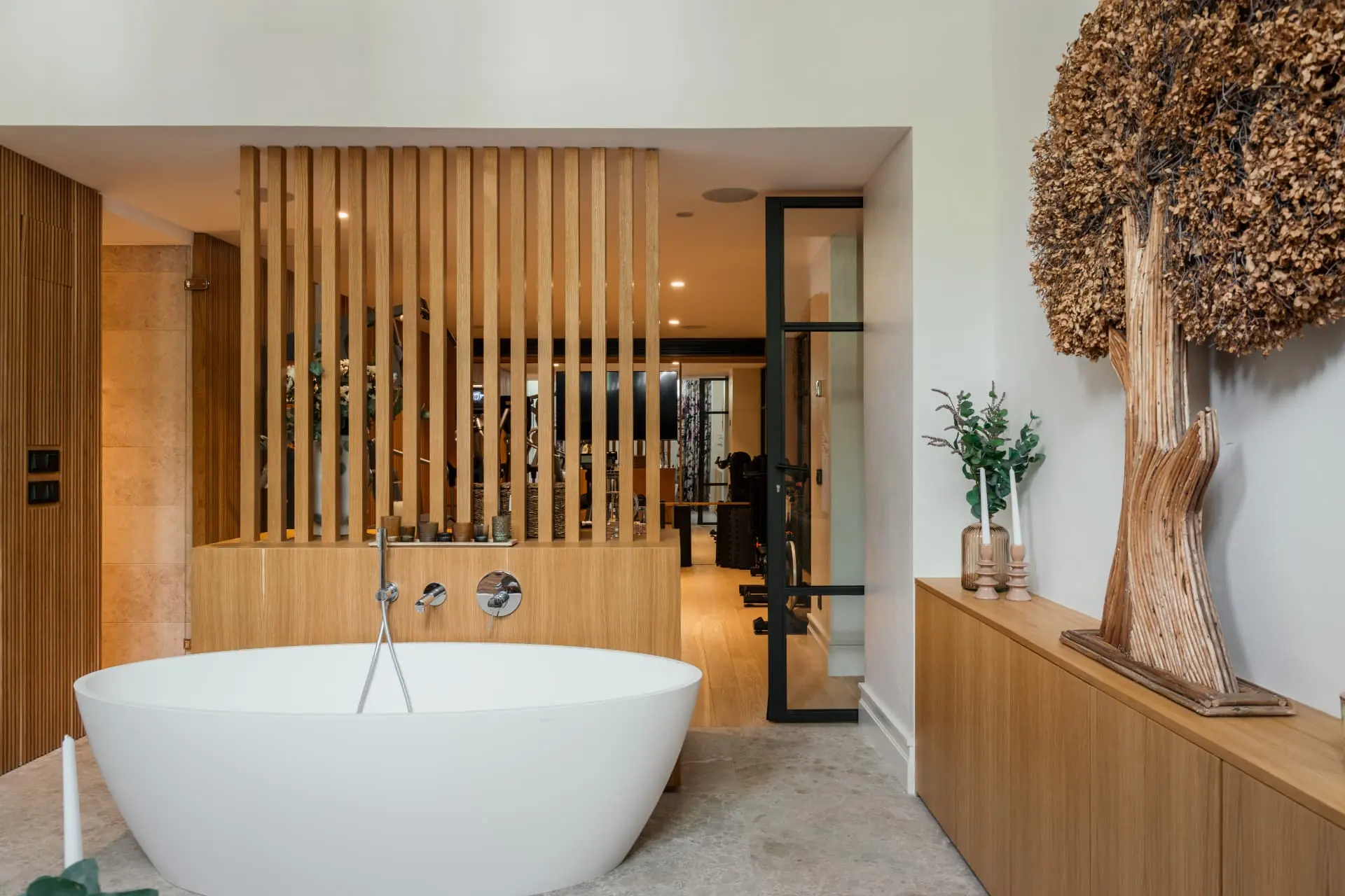 A freestanding stone bath behind an oak slatted screen, the gym beyond